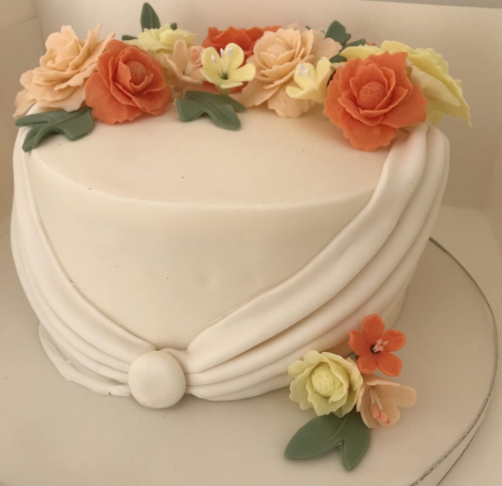 orange and cream flowers on a white wedding cake made in kent